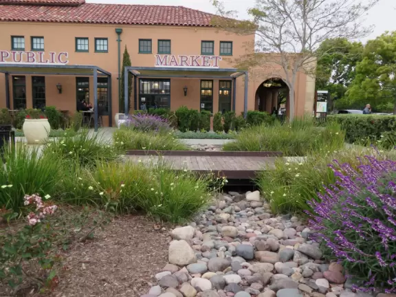 Restaurants with magical gardens, shops, fountain, open grassy areas, historical salmon-pink Spanish Revival architecture at a former naval training center.