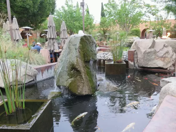 Restaurants with magical gardens, shops, fountain, open grassy areas, historical salmon-pink Spanish Revival architecture at a former naval training center.