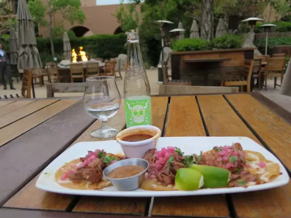 Restaurants with magical gardens, shops, fountain, open grassy areas, historical salmon-pink Spanish Revival architecture at a former naval training center.