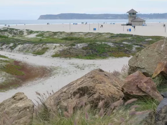 Historic resort with red turrets on foggy beach of fine white sand.