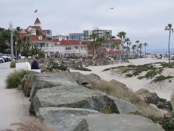 Historic resort with red turrets on foggy beach of fine white sand.