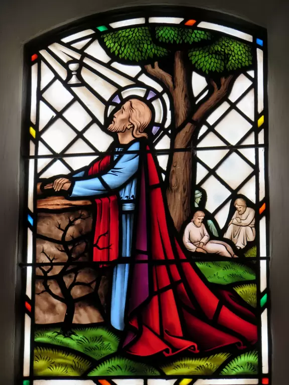 White-washed church with bell towers, rose window, Mary and contented baby Jesus sculpture.