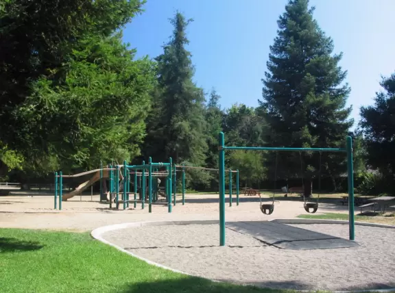 A redwood forest that looks like Northern California, with a playground and spacious knolly lawn.