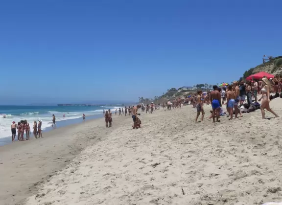 Gorgeous aquamarine water at a long strip of sand with a pier at the end.