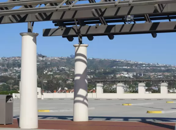 White Spanish-style buildings in an outlet mall, with views of hills from the parking lot.