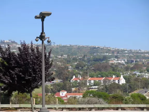 White Spanish-style buildings in an outlet mall, with views of hills from the parking lot.