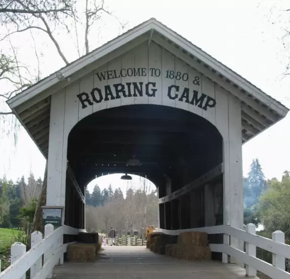 A covered bridge with hay stacks awaits you at the entrance to Roaring Camp.