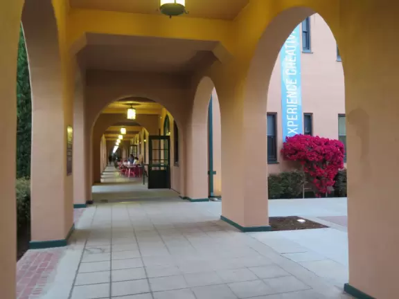 Restaurants with magical gardens, shops, fountain, open grassy areas, historical salmon-pink Spanish Revival architecture at a former naval training center.