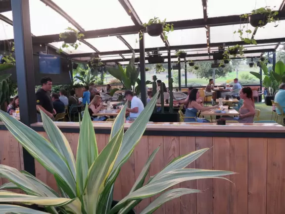 Restaurants with magical gardens, shops, fountain, open grassy areas, historical salmon-pink Spanish Revival architecture at a former naval training center.