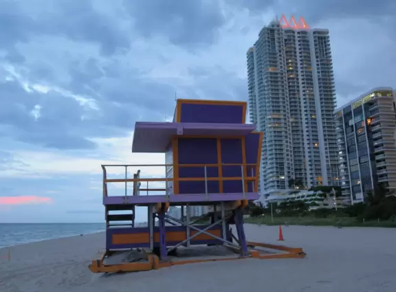 Beautiful beach with purple lifeguard shack, shady playground and park with turtle sculpture, and bike path that runs past it.