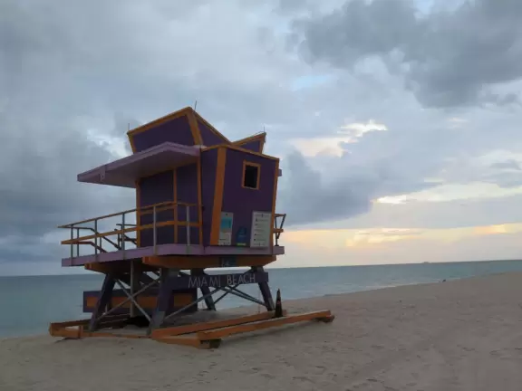 Beautiful beach with purple lifeguard shack, shady playground and park with turtle sculpture, and bike path that runs past it.