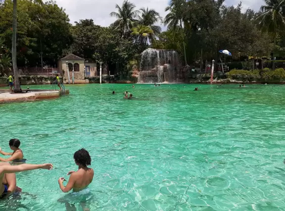 Unique spring-fed historical pool with Venetian-style buildings, bridge, striped posts, waterfall, caves, palms, and banyan tree. Glorious!