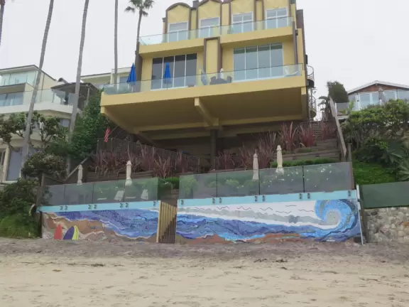 Fun beach with many spots to explore, including rock pools, a walking path with flowers above the sea, basketball courts, a playground, and a lawn by the beach.