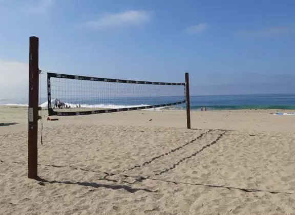 Fun beach with many spots to explore, including rock pools, a walking path with flowers above the sea, basketball courts, a playground, and a lawn by the beach.