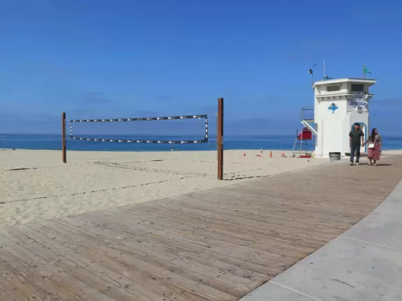 Fun beach with many spots to explore, including rock pools, a walking path with flowers above the sea, basketball courts, a playground, and a lawn by the beach.