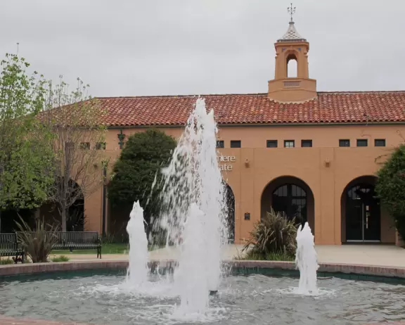 Restaurants with magical gardens, shops, fountain, open grassy areas, historical salmon-pink Spanish Revival architecture at a former naval training center.