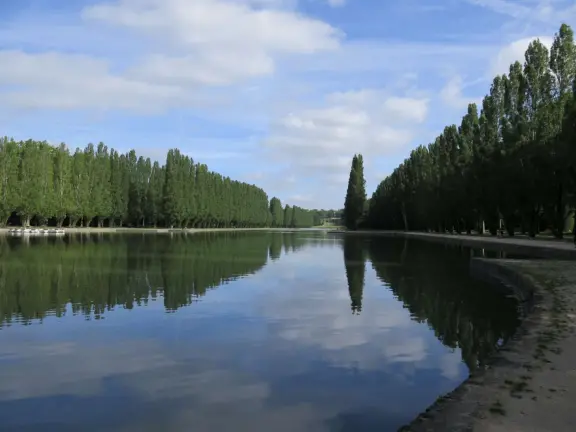 A beautiful park with a grand canal, an impressively high fountain, flower beds, a chateau, and the loveliest trees.