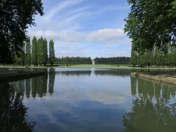 A beautiful park with a grand canal, an impressively high fountain, flower beds, a chateau, and the loveliest trees.
