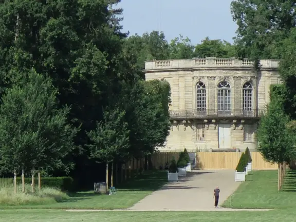 A beautiful park with a grand canal, an impressively high fountain, flower beds, a chateau, and the loveliest trees.