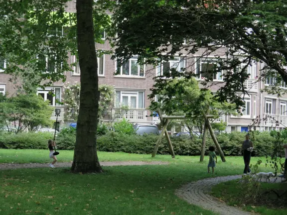Magical park on a canal, with willow trees, huge trees with knobby trunks, sculptures, hydrangea bushes, and a wooden playground with cable..