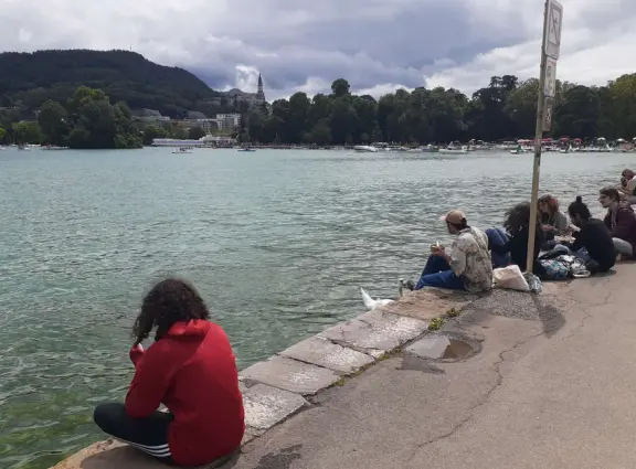 Lakeside park like an arboretum, with tall amazing trees from around the world, statues, modern art sculptures, stunning mountain views, ironwork lovers bridge, and promenade along the blue-green lake.