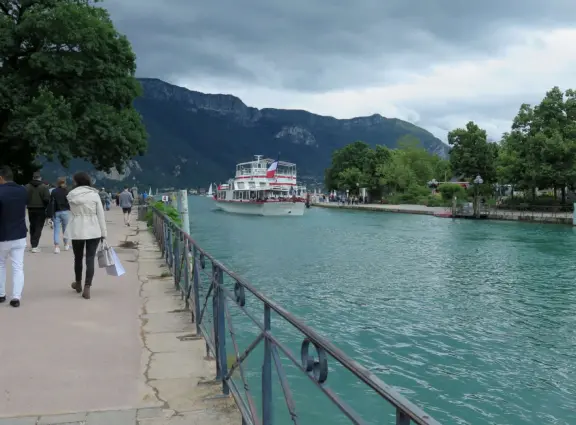 Lakeside park like an arboretum, with tall amazing trees from around the world, statues, modern art sculptures, stunning mountain views, ironwork lovers bridge, and promenade along the blue-green lake.
