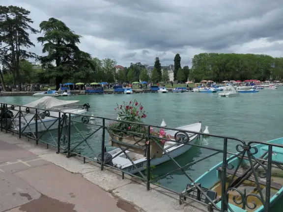 Lakeside park like an arboretum, with tall amazing trees from around the world, statues, modern art sculptures, stunning mountain views, ironwork lovers bridge, and promenade along the blue-green lake.