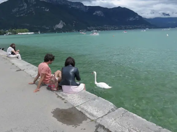 Lakeside park like an arboretum, with tall amazing trees from around the world, statues, modern art sculptures, stunning mountain views, ironwork lovers bridge, and promenade along the blue-green lake.
