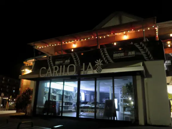 Lovely main street Alii Drive along the crystal clear ocean, backed by high mountains, with historic buildings, oceanfront cafes, and touristy shops.