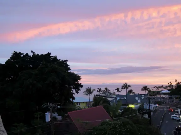Lovely main street Alii Drive along the crystal clear ocean, backed by high mountains, with historic buildings, oceanfront cafes, and touristy shops.