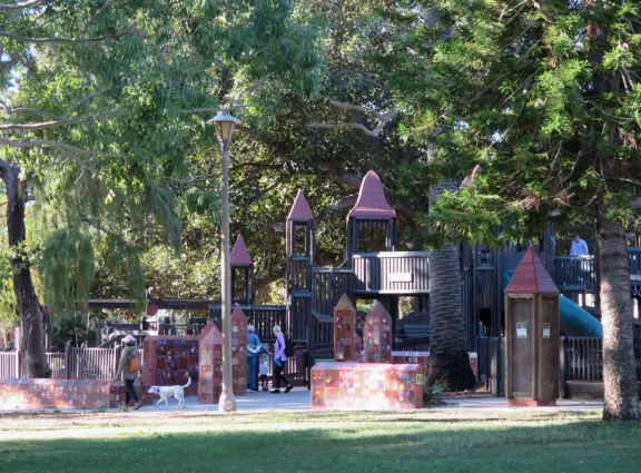 Giant wooden castle playground set among tropical palms.