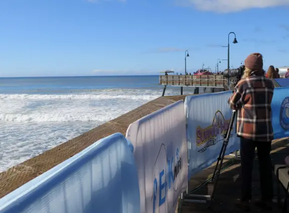 Gorgeous spot with wide pier, surfers carving the waves, whale playground, wide open attractive plaza, Pismo Beach selfie sign, and wooden promenade with views of the hills and sea.