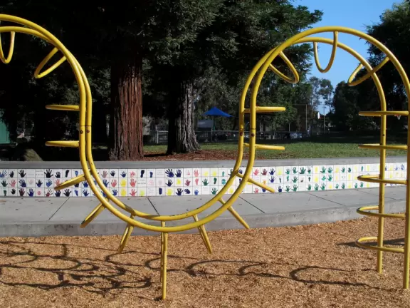 Large park with two colorful play areas and beautiful redwood trees.