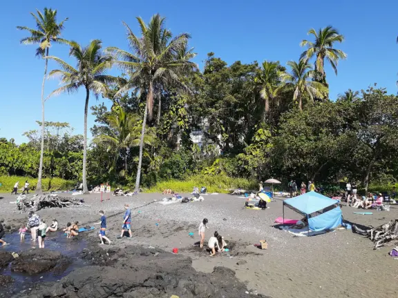 A tiny black sand beach, emerald green springs, grassy knolls, a lifeguard, and warm-water swimming or body boarding.