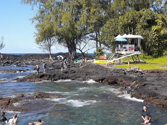 A tiny black sand beach, emerald green springs, grassy knolls, a lifeguard, and warm-water swimming or body boarding.