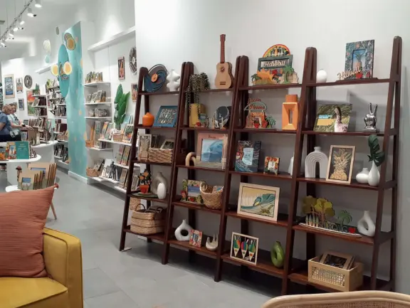 An outdoor mall under a huge banyan tree hung with lanterns. Beautiful flowers by a stream, rock-like seats kids love, and rain fountain.