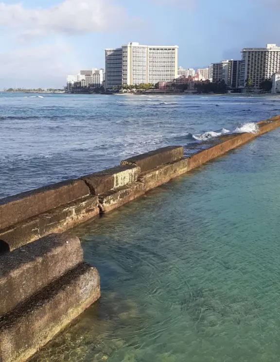 A jetty with a gazebo on the end, in the heart of Waikiki Beach. A popular bodyboarding and snorkeling spot where the reef is inches from your knees!