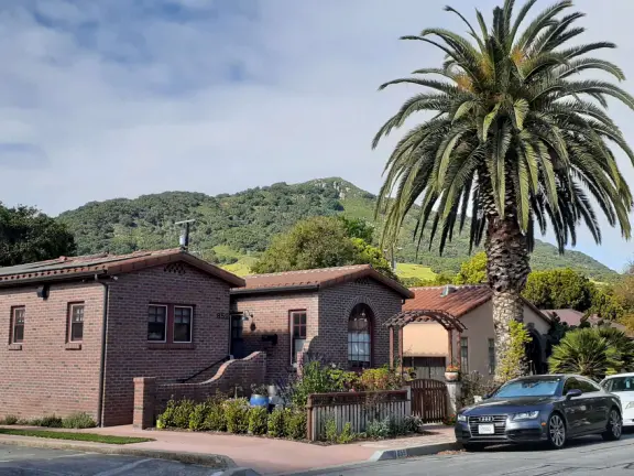 Narrow tree-lined streets in the Anholm District with historic houses and views of Madonna Mountain and Bishop Peak, and a sweet deli.