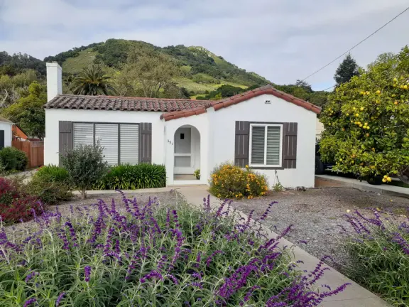 Narrow tree-lined streets in the Anholm District with historic houses and views of Madonna Mountain and Bishop Peak, and a sweet deli.