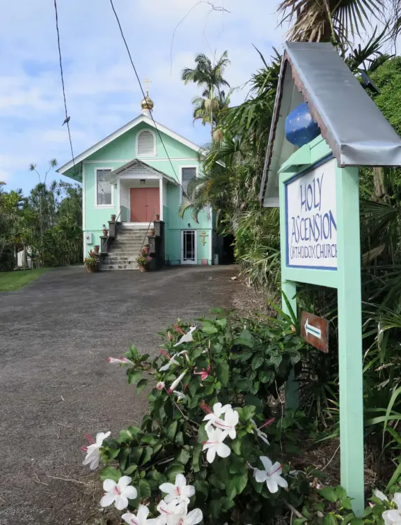 Two blocks of colorful storefronts surrounded by countryside, with a magical feel, on the way to Akaka Falls.