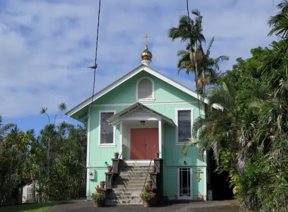 Two blocks of colorful storefronts surrounded by countryside, with a magical feel, on the way to Akaka Falls.