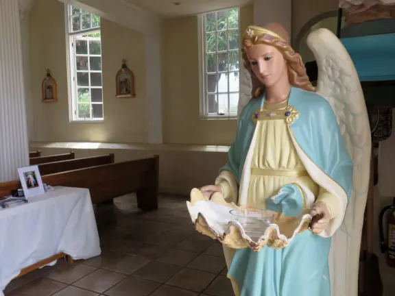 A church that miraculously survived the Lahaina fire. It's garden with mango trees and statues also survived, while beside it is rubble everywhere.