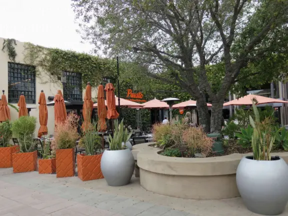 A Spanish-style plaza with cafes and shops, in a historic police headquarters complex.