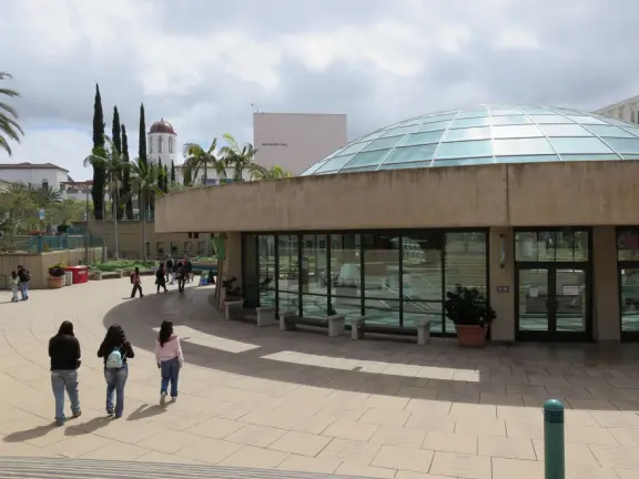Modern campus with tropical blooming trees and Spanish architecture on the northern end of campus.