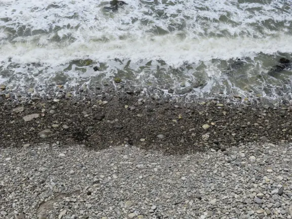 Walkway with benches above the ocean, and steps that lead down to tide pools and beach with reddish-hued sand and lovely cliffs.