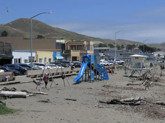 A pretty beachside town, with a wooden pier and wide windy beach with perfect views of Morro Rock, and colorful houses with gardens, backed by gently-sloping hills.