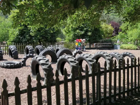 Pristine farm by a hill covered in bright foliage, with oil and vinegar tasting, honey tasting, u-pick, farm store, and adorable kids area with goats, chickens, rabbits, and colorful play areas.