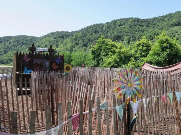 Pristine farm by a hill covered in bright foliage, with oil and vinegar tasting, honey tasting, u-pick, farm store, and adorable kids area with goats, chickens, rabbits, and colorful play areas.