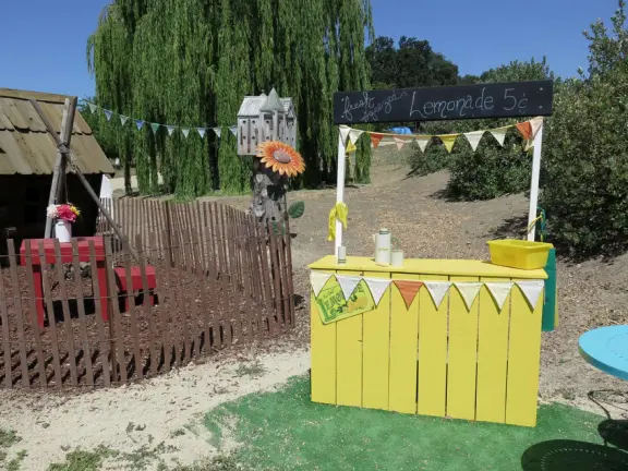 Pristine farm by a hill covered in bright foliage, with oil and vinegar tasting, honey tasting, u-pick, farm store, and adorable kids area with goats, chickens, rabbits, and colorful play areas.