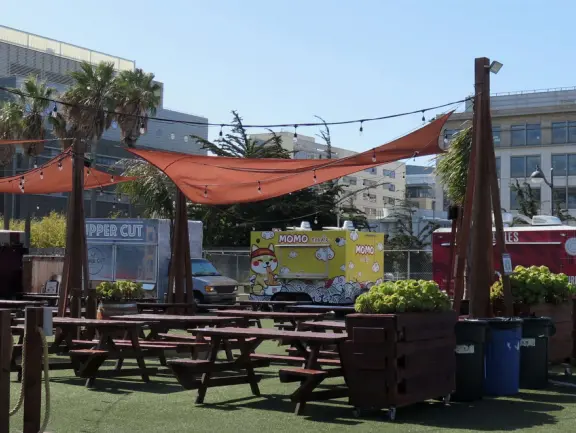 Picnic tables outside food trucks at Spark Social SF. 